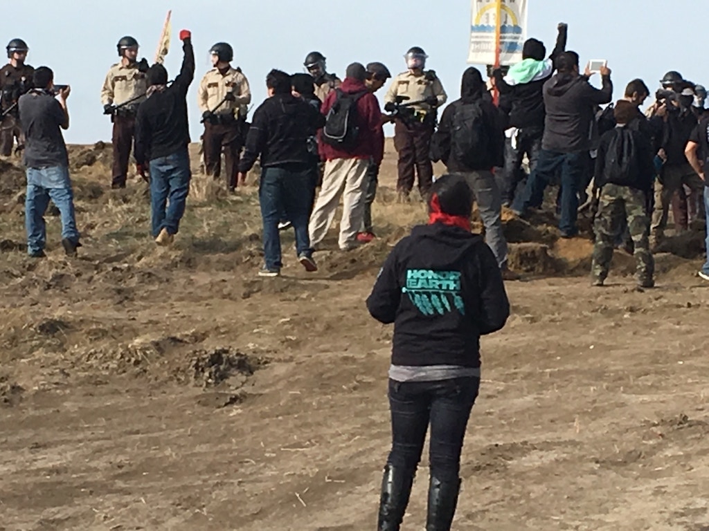 Demonstrators cheer as armed soldiers and law enforcement officers move in to force Dakota Access pipeline protesters off private land in North Dakota on Thursday, Oct. 27, 2016, where they had camped to block construction. The pipeline is to carry oil from western North Dakota through South Dakota and Iowa to an existing pipeline in Patoka, Ill. (Mike McCleary/The Bismarck Tribune via AP)