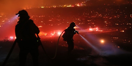 TOPSHOT - Firefighters walk to the fire line at the Lilac fire in Bonsall, California on December 7, 2017.Local emergency officials warned of powerful winds on December 7 that will feed wildfires raging in Los Angeles, threatening multi-million dollar mansions with blazes that have already forced more than 200,000 people to flee. / AFP PHOTO / Sandy Huffaker (Photo credit should read SANDY HUFFAKER/AFP/Getty Images)