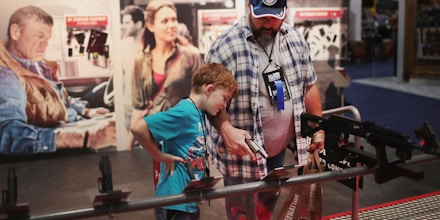 ATLANTA, GA - APRIL 29:  Andrew Farris and his son Eli look over guns fitted with Crimson-Trace sights at the 146th NRA Annual Meetings & Exhibits on April 29, 2017 in Atlanta, Georgia. With more than 800 exhibitors, the convention is the largest annual gathering for the NRA's more than 5 million members.  (Photo by Scott Olson/Getty Images)