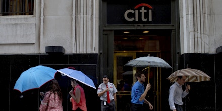 People walk by with umbrellas in front of Citibank in Buenos Aires, Argentina, Friday, Feb. 19, 2016. Citibank says they will sell direct banking operations they had for a century in Argentina, Brazil and Colombia at a time when the three largest economies in South America are suffering setbacks. (AP Photo/Natacha Pisarenko)