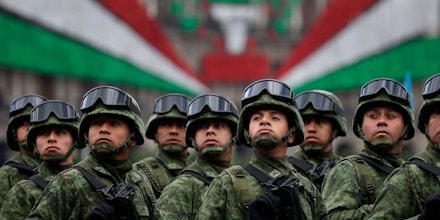 FILE - In this Sept. 16, 2016 file photo, soldiers look up toward the president as they ride past the National Palace during the annual Independence Day military parade in Mexico City's main square, known as the Zocalo. A bill to give legal justification for Mexico’s armed forces to assume police roles advanced in the country's Congress, Thursday, Nov. 30, 2017, over objections by rights groups and opposition legislators who say it would provide for an open-ended militarization.  (AP Photo/Rebecca Blackwell, File)