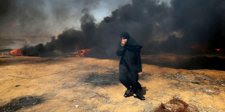 A Palestinian woman covers her face as smoke billows around her during clashes with Israeli forces along the border with the Gaza strip east of Khan Yunis on May 11, 2018, as Palestinians demonstrate for the right to return to their historic homelands in what is now Israel. - Over fifty Palestinians have been killed by Israeli fire since protests and clashes began on March 30 calling for Palestinian refugees to be able to return to their former homes in what is now Israel. (Photo by SAID KHATIB / AFP)        (Photo credit should read SAID KHATIB/AFP/Getty Images)
