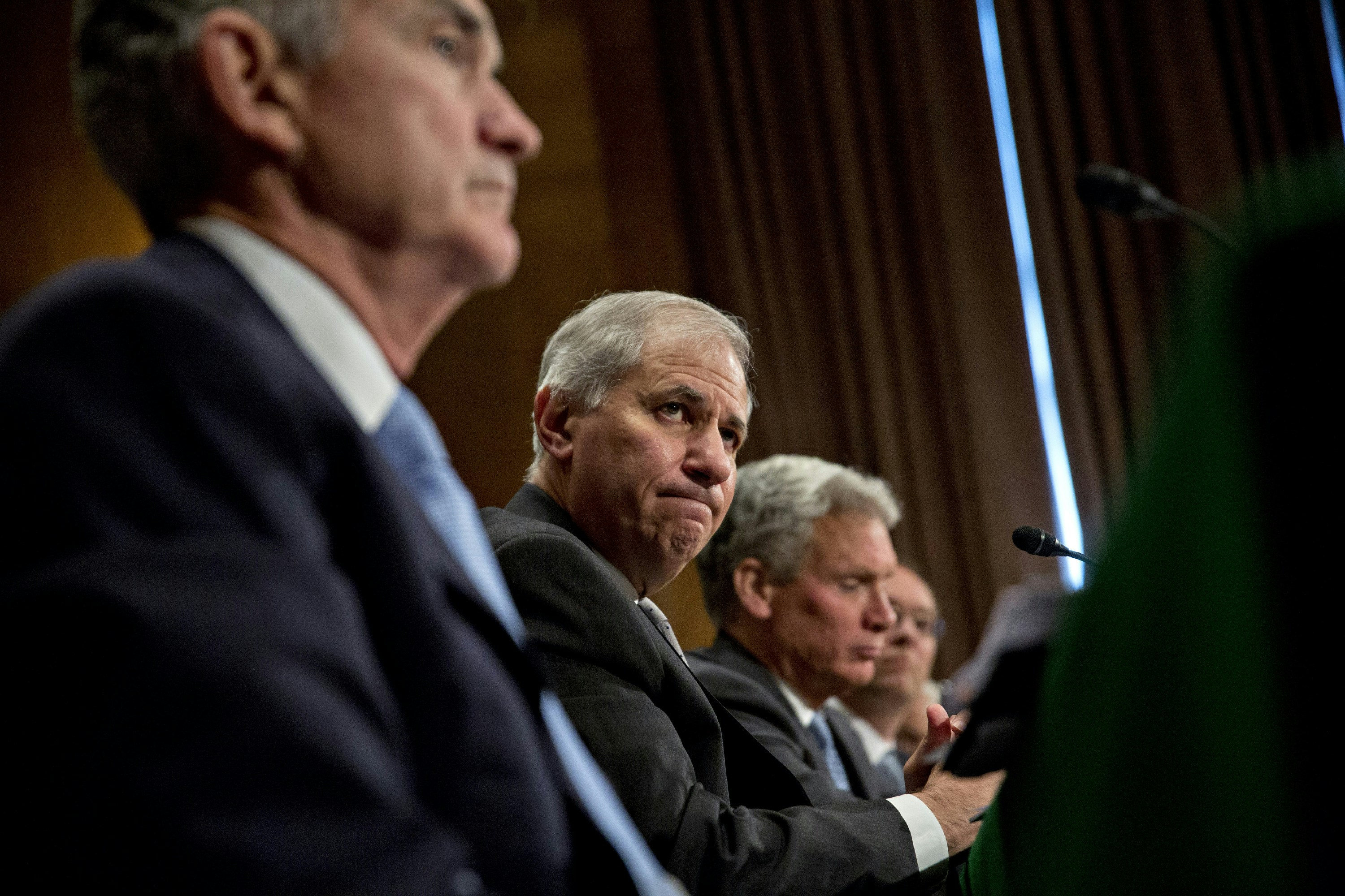 Martin Gruenberg, chairman of the Federal Deposit Insurance Corp. (FDIC), center, and Jerome Powell, governor of the U.S. Federal Reserve, left, listen during a Senate Banking Committee hearing in Washington, D.C., U.S., on Thursday, June 22, 2017. Top U.S. banking regulators are sprinting to ease the Volcker Rule, stress tests and other constraints on Wall Street after the Trump administration issued a long list of proposals last week for rolling back post-crisis financial rules. Photographer: Andrew Harrer/Bloomberg via Getty Images