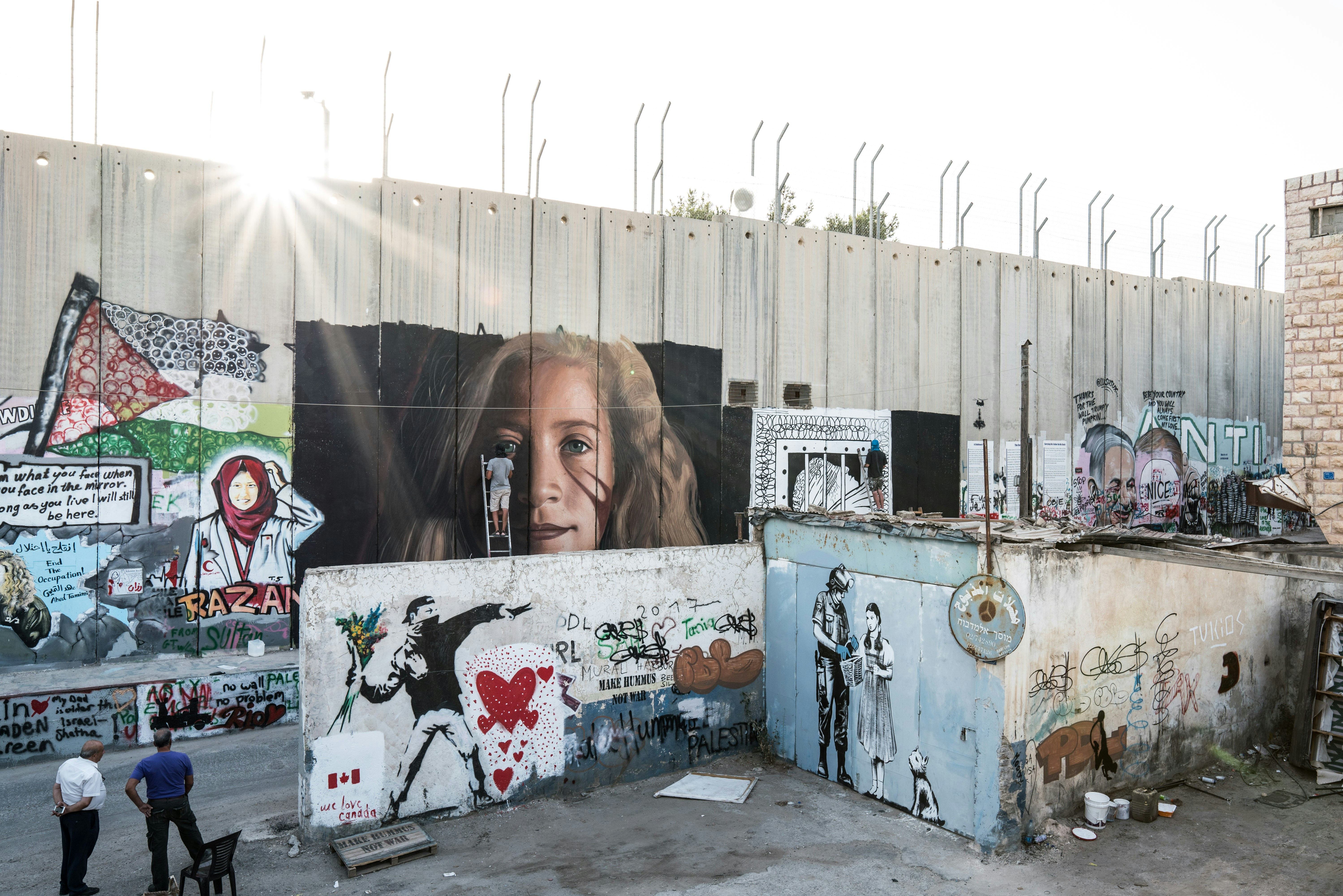 An Italian activist paints a portrait of Palestinian Ahed Tamimi on a part of the Israeli separation wall in Bethlehem on July 25, 2018.