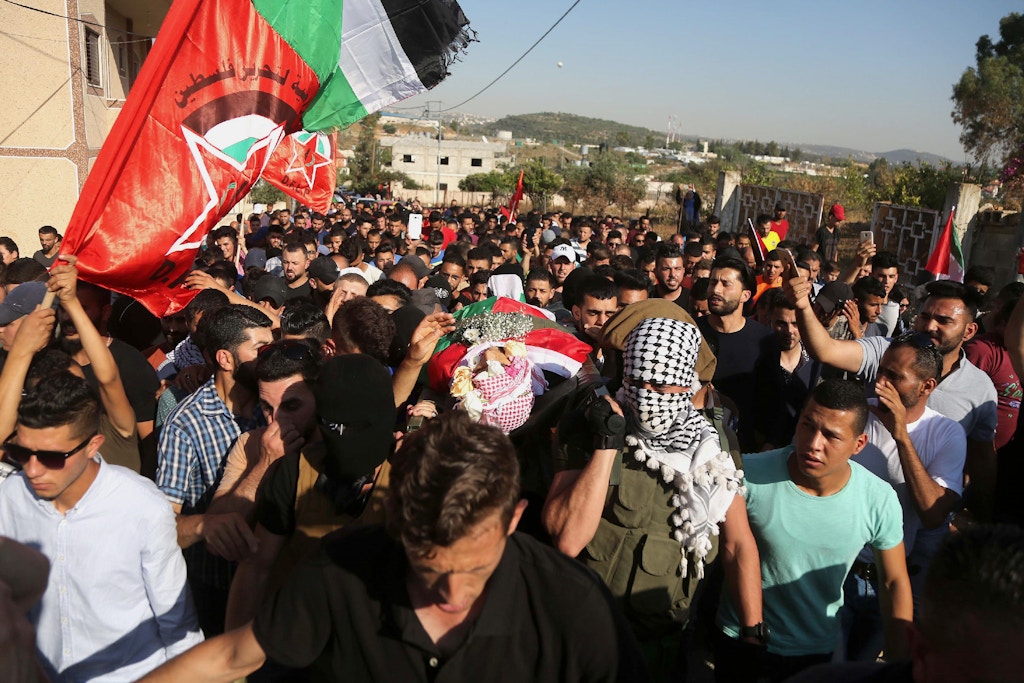 RAMALLAH, WEST BANK - JUNE 06: Palestinians carry the dead body of Ezz al-Tamimi, 21, who was killed by Israeli forces, at a checkpoint, as Israeli soldiers intervene them during his funeral ceremony near Nabi Saleh district of Ramallah, in West Bank on June 06, 2018. (Photo by Issam Rimawi/Anadolu Agency/Getty Images)