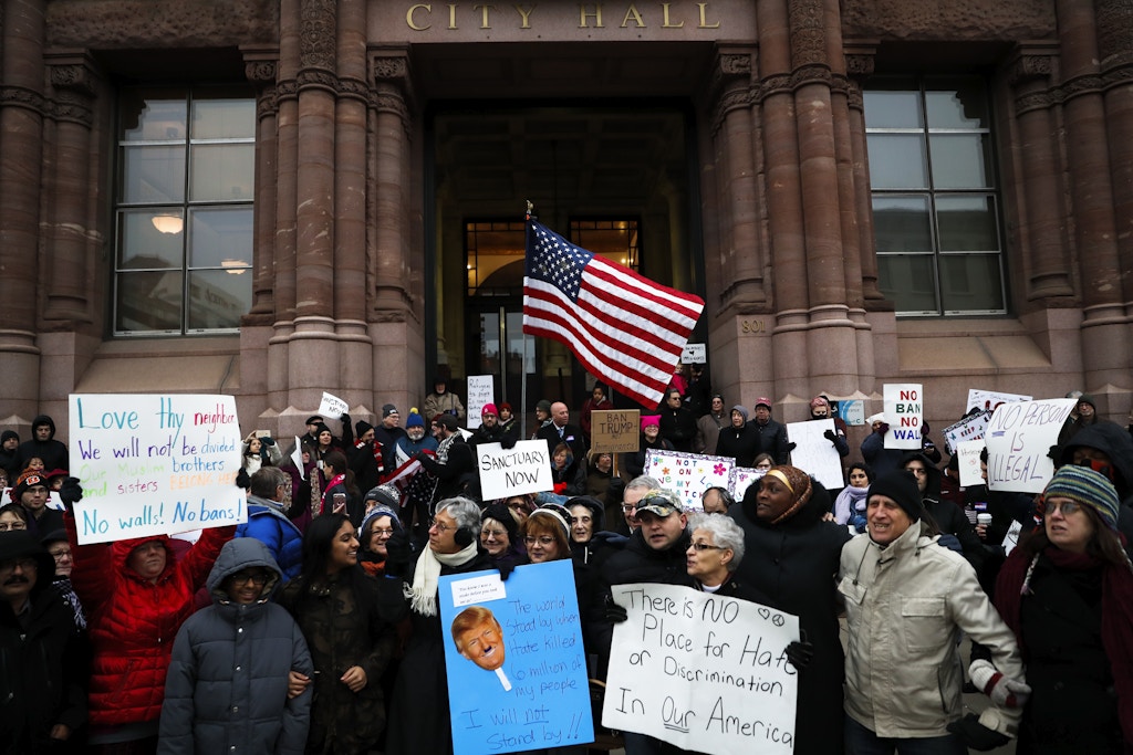Demonstrators gather in solidarity against President Donald Trump's executive order temporarily banning immigrants from seven Muslim-majority countries from entering the U.S. and suspending the nation’s refugee program Monday, Jan. 30, 2017, outside City Hall in Cincinnati. In addition, earlier in the day Mayor John Cranley declared Cincinnati a "sanctuary city," meaning city will not enforce federal immigration laws against people who are here illegally, in keeping with current policy. (AP Photo/John Minchillo)