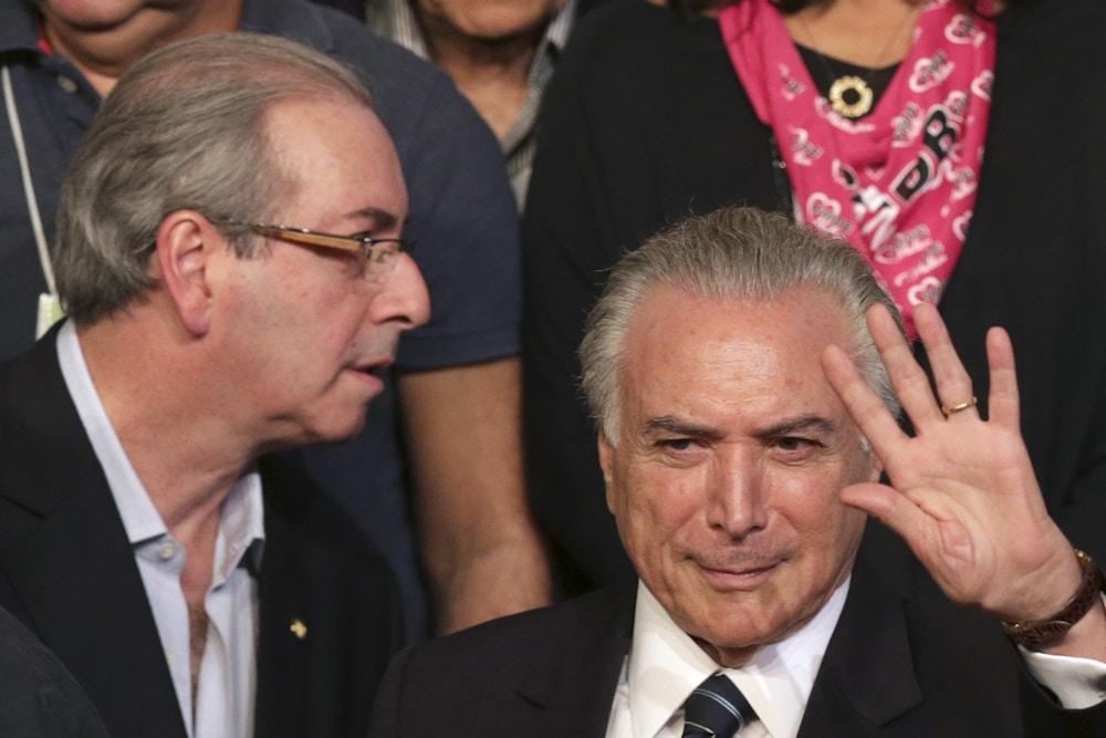 Brazil's Vice President Michel Temer waves during the Brazilian Democratic Movement Party, (PMDB), national convention in Brasilia, Brazil, Saturday, March 12, 2016. The PMDB is considering abandoning its alliance with the Workers' Party that began during Luiz Inacio Lula da Silva's government. Silva served as Brazil's president from Jan. 2003 to Jan. 1 2011. Pictured on left is the speaker of Brazil's lower house of Congress Eduardo Cunha. (AP Photo/Eraldo Peres)