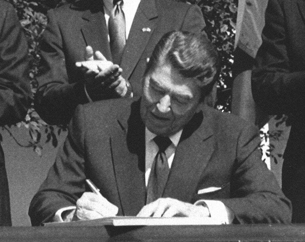 President Ronald Reagan signs legislation implementing the U.S.-Canada free trade agreement during a ceremony at the White House, Sept. 28, 1988.  (AP Photo/Scott Stewart)