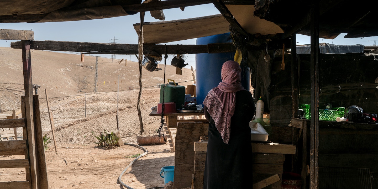 Palestinian Bedouin XXX washes dishes at her home in the village of Al-Khan Al-Ahmar on July 26, 2018