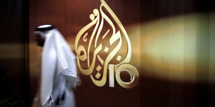 FILE -- In this Nov. 1, 2006 file photo, a Qatari employee of Al Jazeera Arabic language TV news channel walks past the logo of Al Jazeera in Doha, Qatar. Hackers allegedly broke into the website of Qatar's state-run news agency and published a fake story quoting the ruling emir, authorities there said Wednesday, May 24, 2017, as Saudi Arabia and the United Arab Emirates responded by blocking Qatari media, including broadcaster Al-Jazeera. (AP Photo/Kamran Jebreili, File)