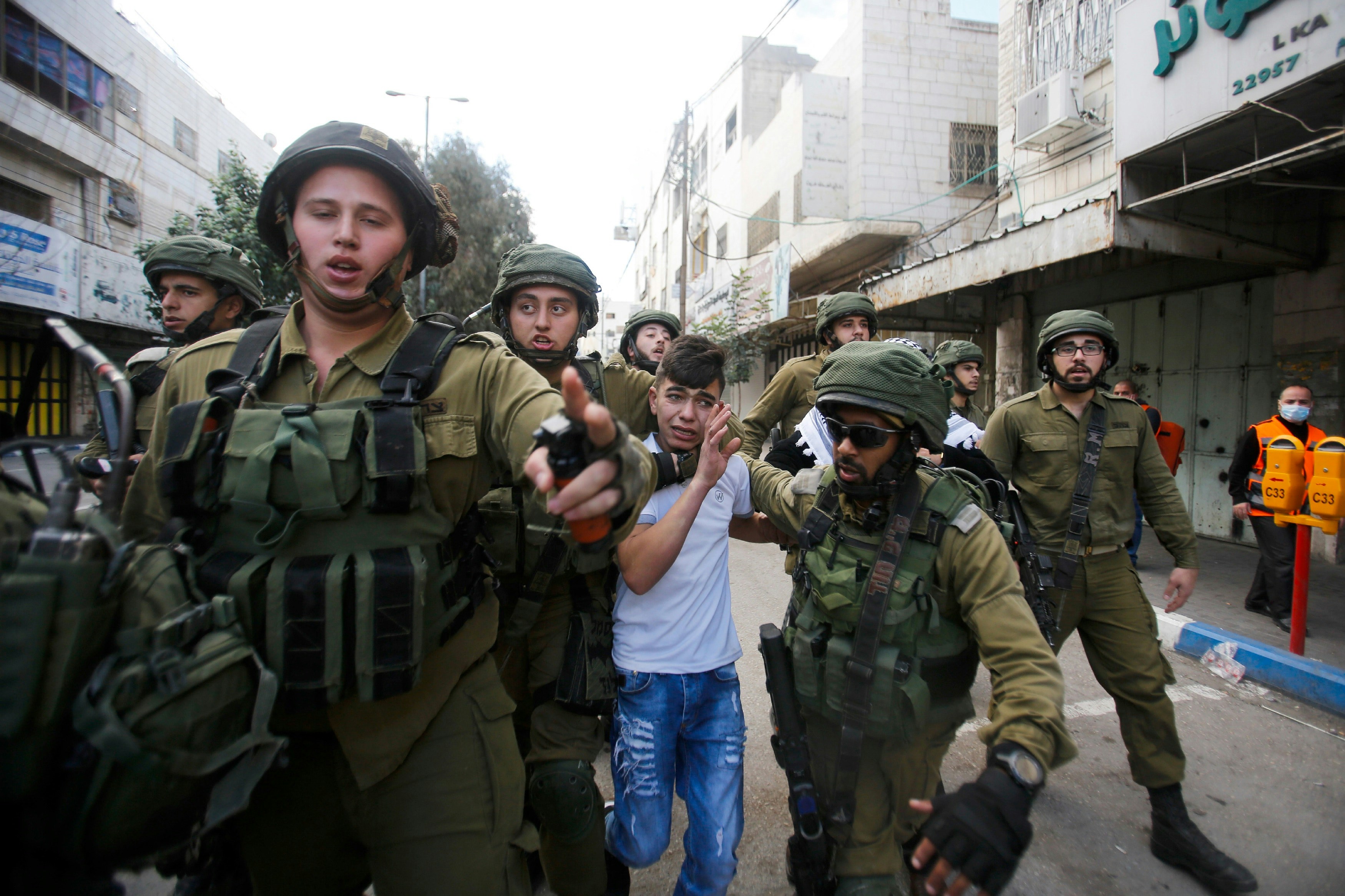 Soldados israelenses detêm um garoto palestino em Hebron em 15 de dezembro de 2017, durante um protesto contra a decisão do presidente norte-americano Donald Trump de reconhecer Jerusalém como a capital de Israel.