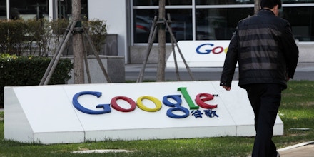 A pedestrian walks past the Google Inc. logo displayed outside the building housing the company's China headquarters in Beijing, China, on Monday, Nov. 12, 2012. Google Inc. reported higher traffic patterns on its sites in China after the company earlier said there was an unusual decline in the country, and an Internet monitor said company services were blocked there. Photographer: Tomohiro Ohsumi/Bloomberg via Getty Images