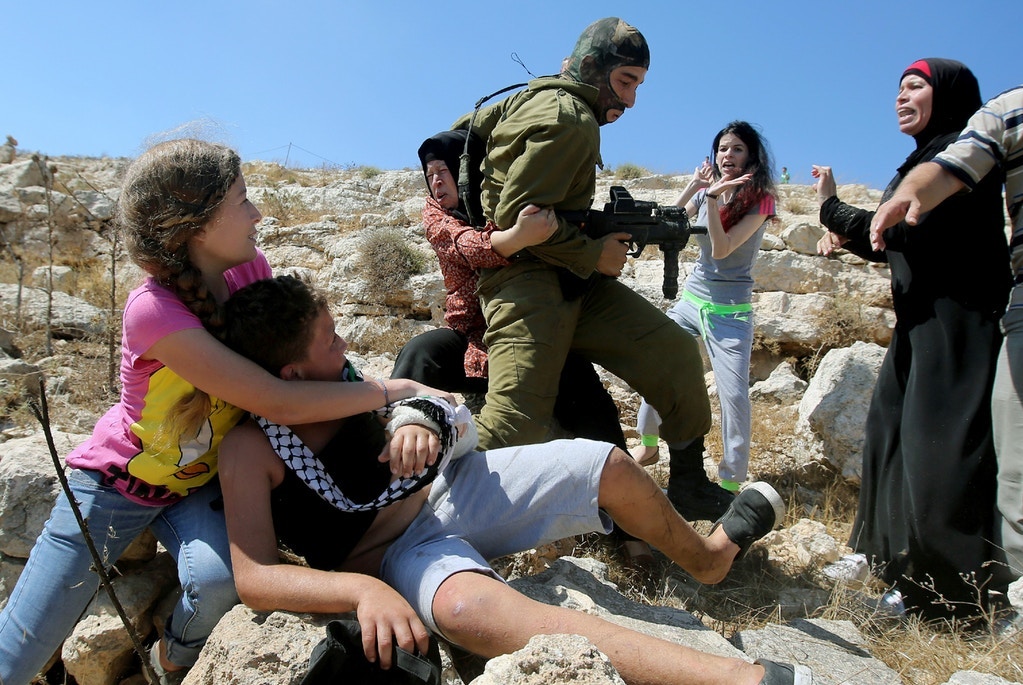 Ahed, à esquerda, abraça o irmão depois que ela e outras mulheres palestinas lutaram para libertá-lo de um soldado israelense durante confrontos entre forças de segurança israelenses e manifestantes palestinos em 28 de agosto de 2015.