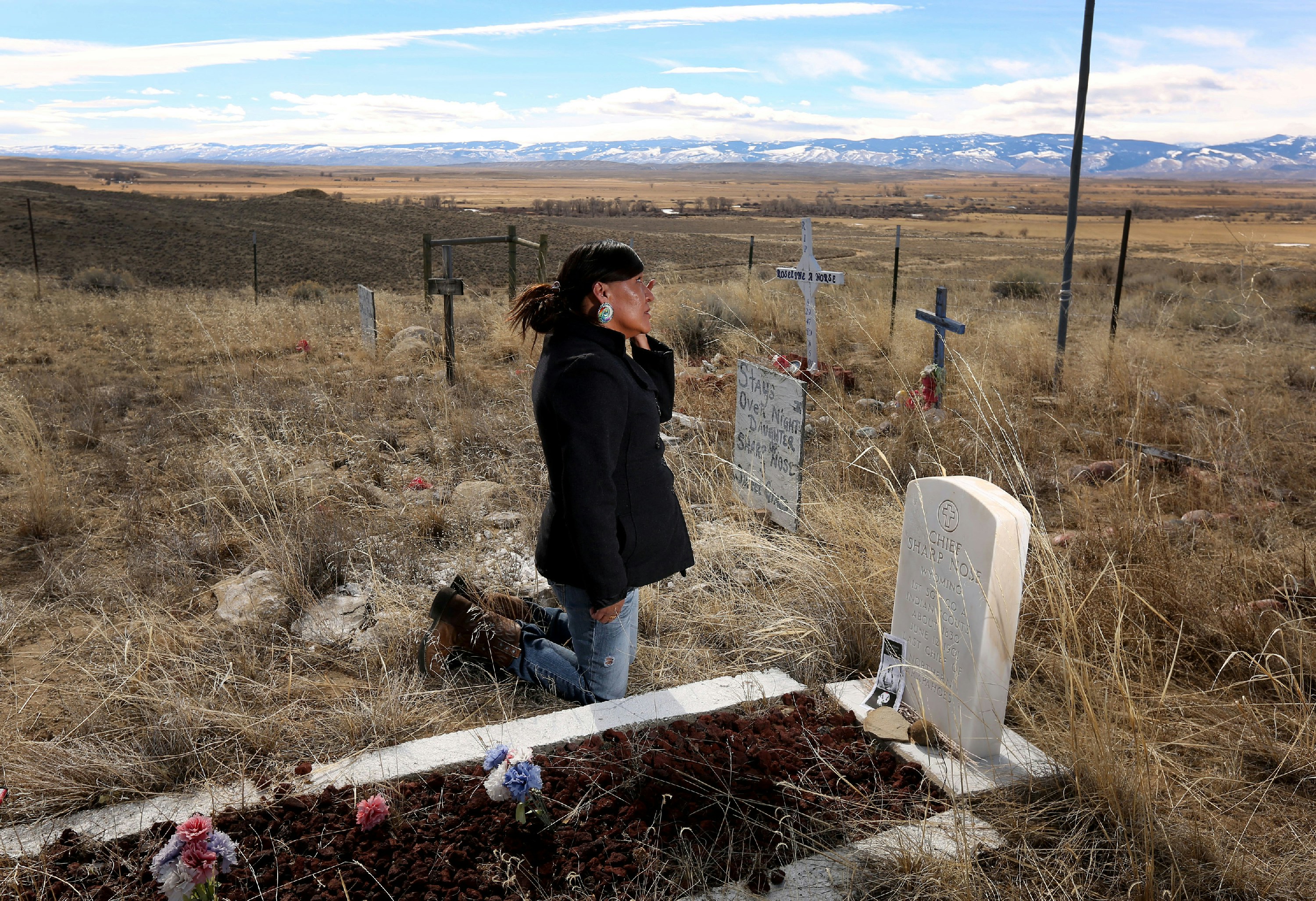 ADVANCE FOR WEEKEND EDITIONS - In this March 1, 2016 photo, Yufna Soldier Wolf wipes away tears while kneeling at the grave of her great-grandfather, Chief Sharp Nose of the Northern Arapaho Tribe, at the family cemetery on the Wind River Reservation near Riverton, Wyo. Soldier Wolf is seeking the remains of her great-uncle Little Chief, who died while attending Carlisle Indian School in Carlisle, Pennsylvania. (Dan Cepeda/The Casper Star-Tribune via AP) MANDATORY CREDIT