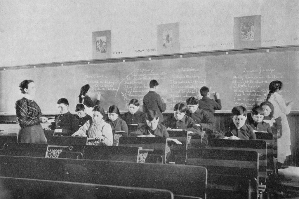 Uma sala de aula da segunda série na Carlisle Indian School, ao redor de 1902.