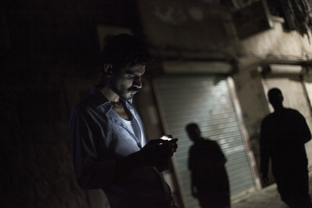 In this Friday, Sept. 21, 2012 photo, a Syrian man looks at his mobile phone in the Bustan al-Qasr neighborhood of Aleppo, Syria. The Britain-based Syrian Observatory for Human Rights said Friday that nearly 30,000 Syrians have been killed during the 18-month uprising against the Assad regime. (AP Photo/ Manu Brabo)