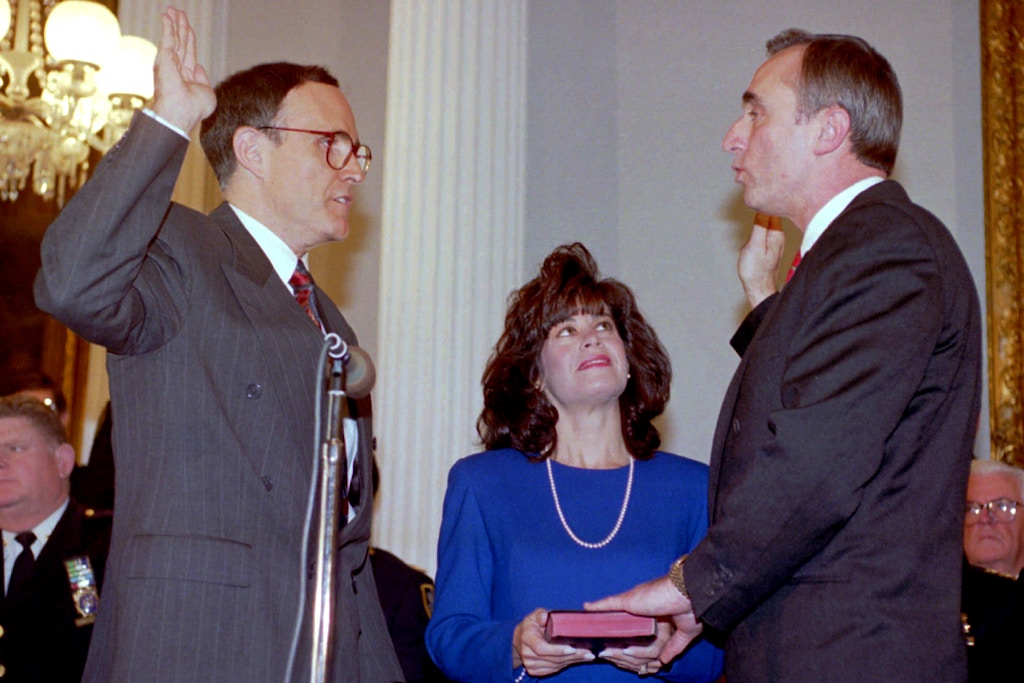 New York City Mayor Rudolph Giuliani, left, adminsters the oath of office to Police Commissioner William J. Bratton at New York City Hall ceremonies Tuesday, Jan. 11, 1994. Bratton's wife, Cheryl Fiandaca, holds the Bible for the former Boston police commissioner. (AP Photo/Richard Drew)