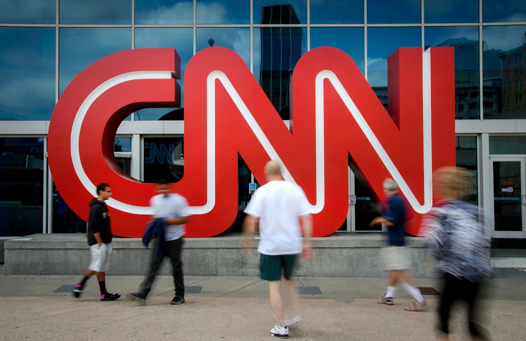 Pedestrians pass in front of CNN signage displayed at the network's headquarters building in Atlanta, Georgia, U.S., on Friday, Aug. 1, 2014. Time Warner is a "long, long way from a transaction," former Chief Executive Officer Richard Parsons said, adding the home of HBO, CNN and the Warner Bros. studio would be better off remaining independent. Photographer: Michael A. Schwarz/Bloomberg via Getty Images