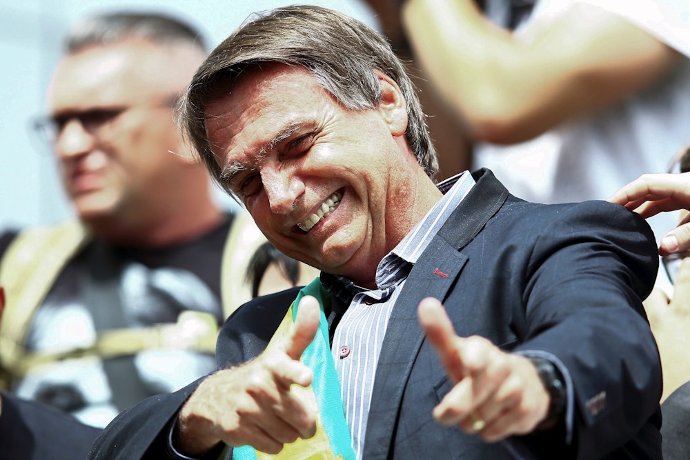 Right-wing federal deputy and presidential candidate Jair Bolsonaro, gives a thumbs up to supporters during a rally at Afonso Pena airport in Curitiba, Brazil on March 28, 2018. Bolsonaro, who has repeatedly praised Brazil's two-decade-long military dictatorship, taunted Lula, calling him a "bandit," and challenging him in Curitiba to see "who can get the most people out on to the streets without paying them." / AFP PHOTO / Heuler Andrey (Photo credit should read HEULER ANDREY/AFP/Getty Images)