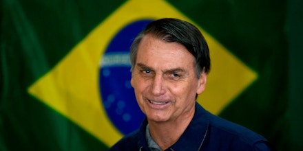 Brazil's right-wing presidential candidate for the Social Liberal Party (PSL) Jair Bolsonaro walks in front of the Brazilian flag as he prepares to cast his vote during the general elections, in Rio de Janeiro, Brazil, on October 7, 2018. - Polling stations opened in Brazil on Sunday for the most divisive presidential election in the country in years, with far-right lawmaker Jair Bolsonaro the clear favorite in the first round. About 147 million voters are eligible to cast ballots and choose who will rule the world's eighth biggest economy. New federal and state legislatures will also be elected. (Photo by Mauro PIMENTEL / AFP)        (Photo credit should read MAURO PIMENTEL/AFP/Getty Images)