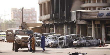 As forças de segurança ficam em frente ao exterior queimado do Splendid Hotel em Ouagadougou, Burkina Faso, em 16 de janeiro de 2016, um dia depois de um ataque da Al Qaeda ter matado 30 pessoas em um restaurante do outro lado da rua.