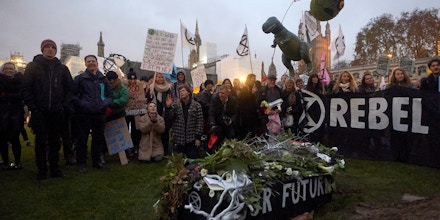 Environmental activists gather around a mock 'coffin' with 