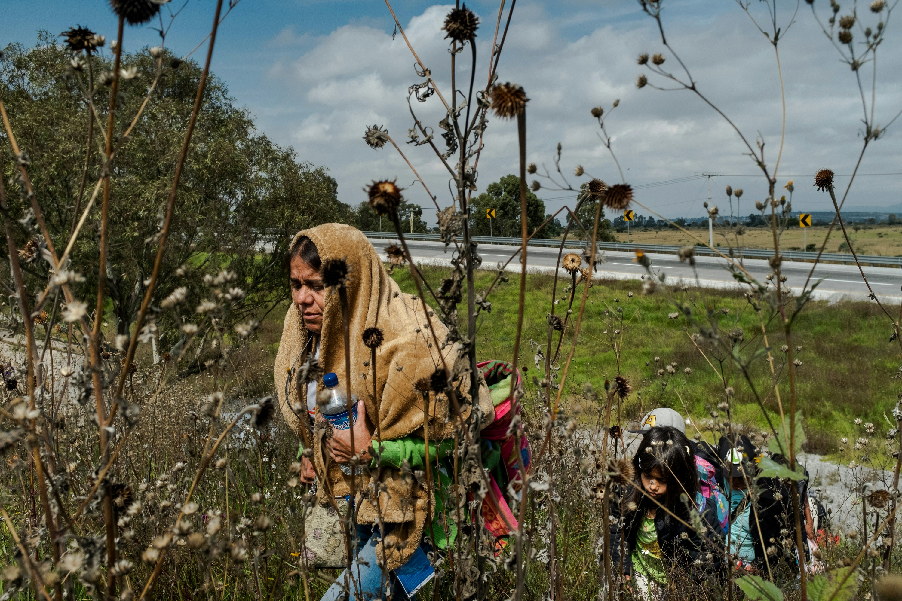 A Central American migrant woman walks up a hill near a truck rest stop after jumping off a cargo truck carrying migrants from the Central American caravan on its way to the city of Santiago de Querétaro on November 10, 2018. Earlier that morning thousands of migrants from the first caravan exited Mexico City where for over a week they rested and waited to continue their journey northbound to Tijuana.Photographer: Mark Abramson