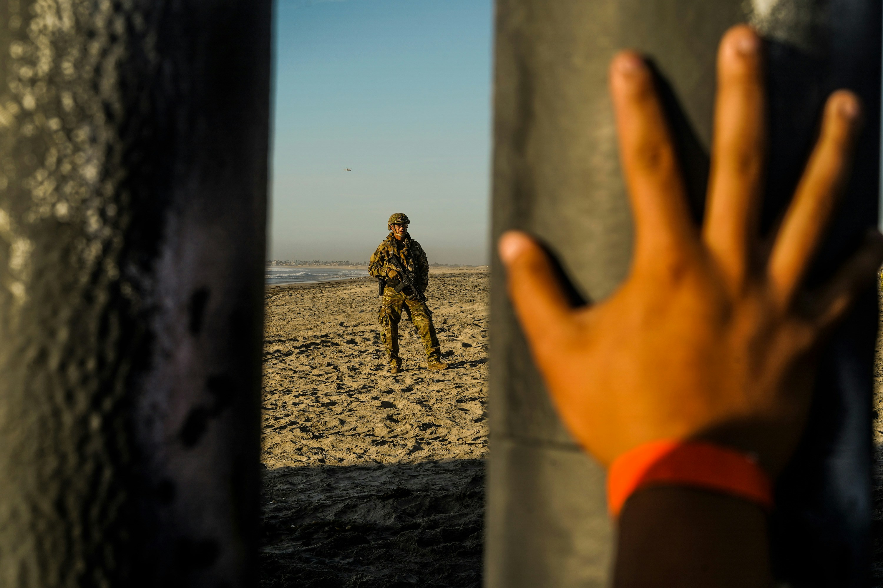 A soldier is seen on the US side of the border fence while a Honduran migrant's hand is placed on the border fence on Mexico side in Tijuana, Mexico on November 16, 2018.Thousands of Central American migrants, who are trying to go to the US, arrived in the US/Mexico border town of Tijuana in mid November 2018 however most of them have hard time to find a way to cross the border to the US. Go Nakamura