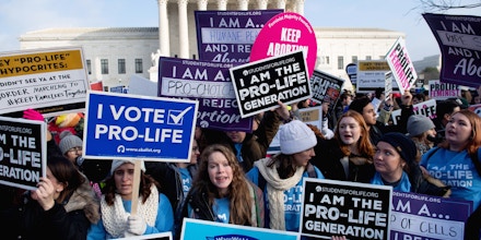 Pro-choice activists hold signs in response to anti-abortion activists participating in the 