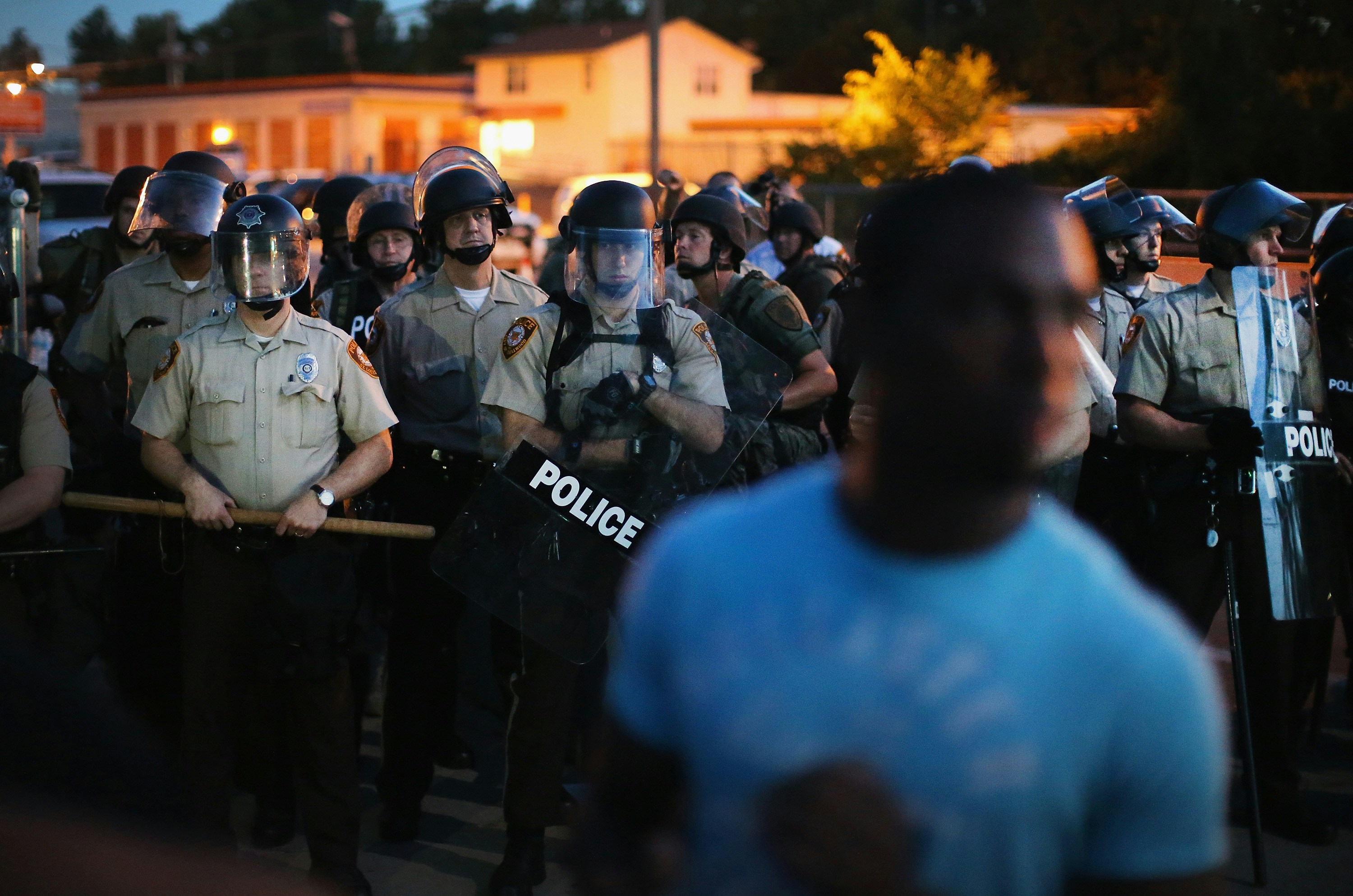 FERGUSON, MO - AUGUST 13:  Police stand watch as demonstrators protest the shooting death of teenager Michael Brown on August 13, 2014 in Ferguson, Missouri. Brown was shot and killed by a Ferguson police officer on Saturday. Ferguson, a St. Louis suburb, is experiencing its fourth day of violent protests since the killing.  (Photo by Scott Olson/Getty Images)
