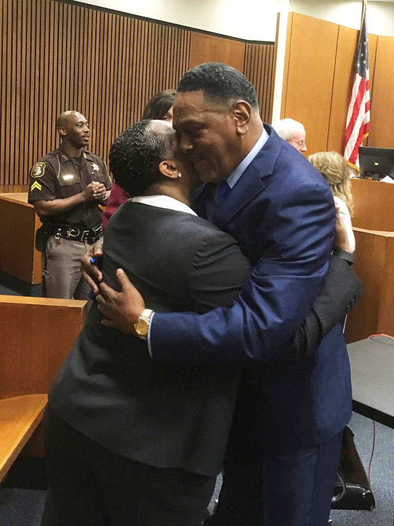 Richard Phillips, right,  hugs Det. Patricia Little in a Wayne County, Mich., courtroom on Wednesday, March 28, 2018, in Detroit. Phillips, a Michigan man whose murder conviction was thrown out after he spent 45 years in prison will not face a second trial. (AP Photo/Ed White)