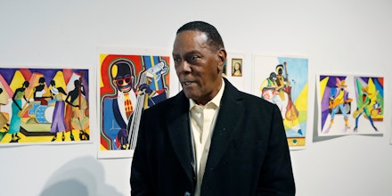 In this Thursday, Jan. 17, 2019 photo, Richard Phillips stands next to some of his artwork during an interview at the Community Art Gallery in Ferndale, Mich. Phillips was exonerated of murder in 2018 after 45 years in prison. Lawyers say he should be entitled to more than $2 million under Michigan's wrongful conviction law, but the state so far is resisting. So Phillips, 73, is selling some of his 400-plus watercolors that he painted in prison. (AP Photo/Carlos Osorio)
