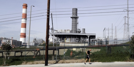 A jogger runs past the Scattergood power plant Tuesday, Feb. 12, 2019, in Los Angeles. Los Angeles will abandon a plan to spend billions of dollars rebuilding three natural gas power plants as the city moves toward renewable energy, Mayor Eric Garcetti said Monday. (AP Photo/Marcio Jose Sanchez)