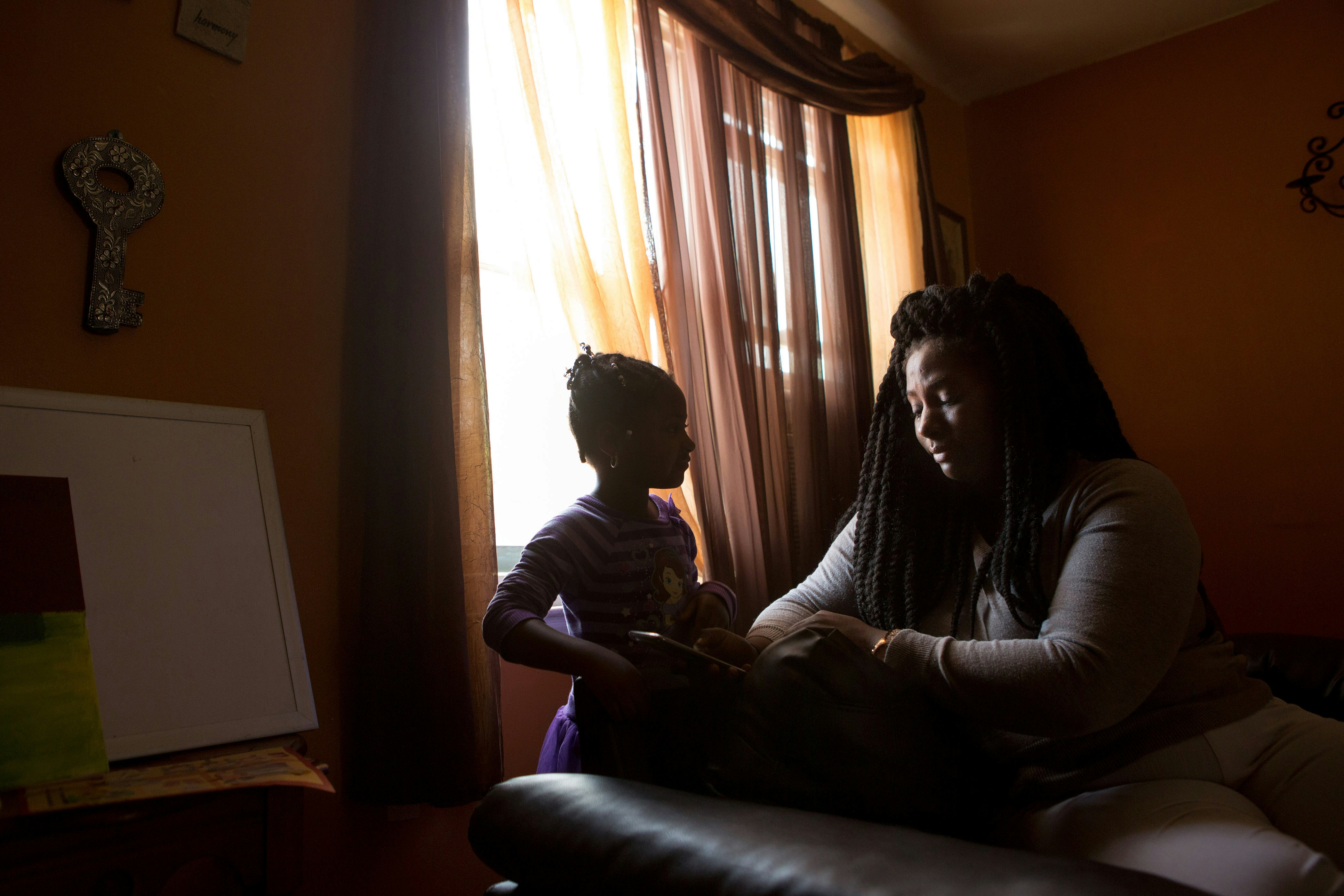 Kelly Holsey cries as she and her daughter Peyton Carter, 5, look at photos of her fiancÈ Keith Davis Jr. after his police encounter at Holsey's mother's home in the suburbs of Baltimore, Maryland, April 23, 2016. Davis was shot by police and is now in prison charged with murder-- all unfairly according to Holsey. Holsey and her daughter drew henna tattoos with Davis' name on their arms. (photo by Allison Shelley)
