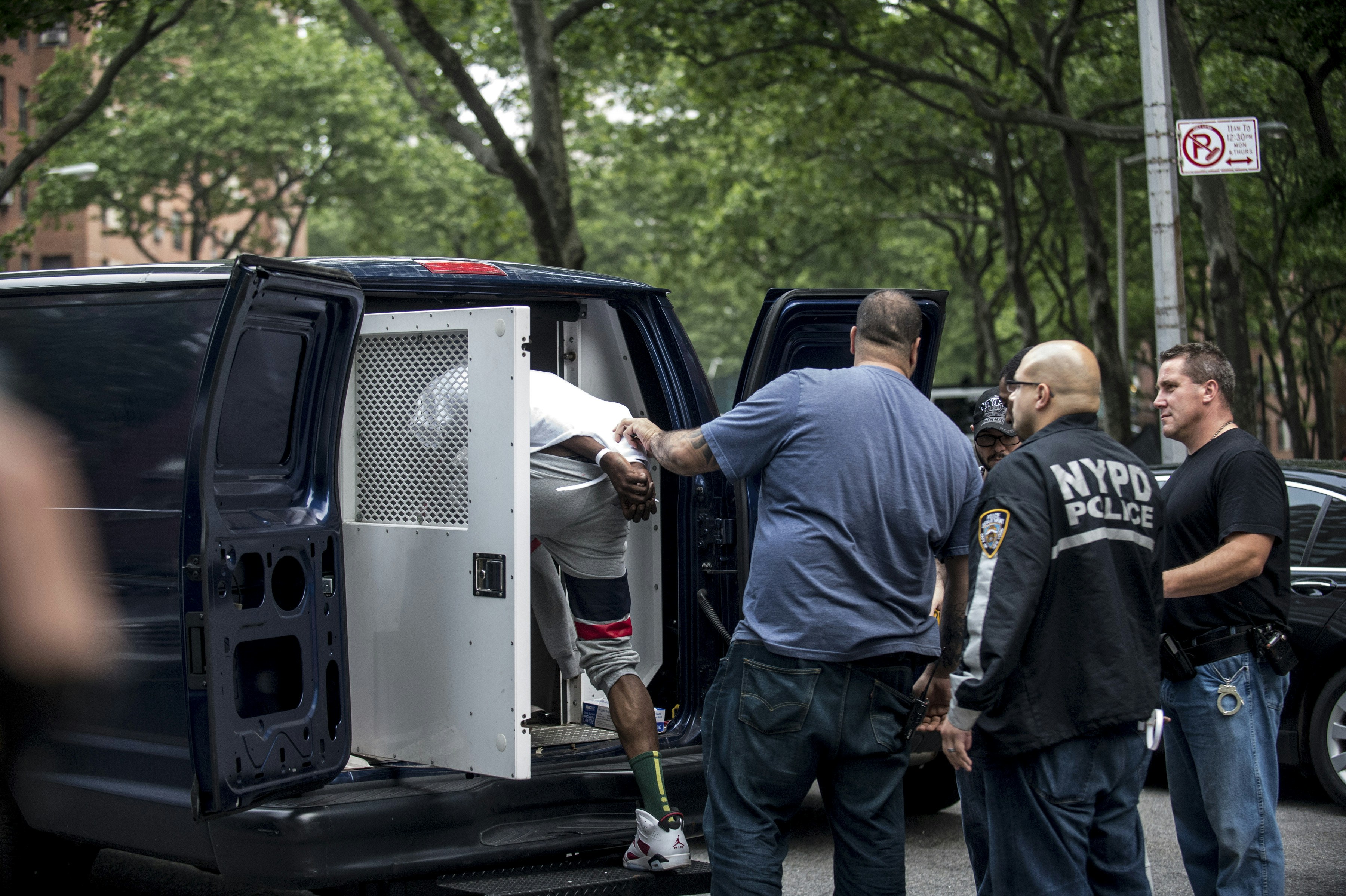 One of the dozens of suspected gang members corralled in simultaneous early-morning raids is led into a police van in the Harlem neighborhood of New York, June 4, 2014. The indictment cites 103 people, roughly 30 of whom were already in jail, with two killings, 15 shootings, and a host of other crimes. (Robert Stolarik/The New York Times)
