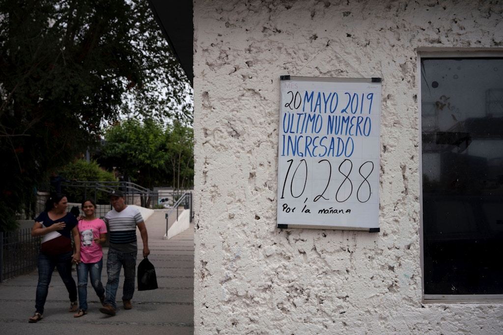 People walk past a sign reading "last number entered" in Ciudad Juarez, Chihuahua state, on May 20, 2019. - About 7,000 migrants are waiting to enter the United States via El Paso, either by the metered number system, or those which are part of the remain in Mexico policy, Migrant Protection Protocols. Those that are part of MPP are made to wait out their asylum claims on the Mexican side of the Border, where they are vulnerable to criminals looking for an easy target, extortionists, corrupt police, among other dangers.