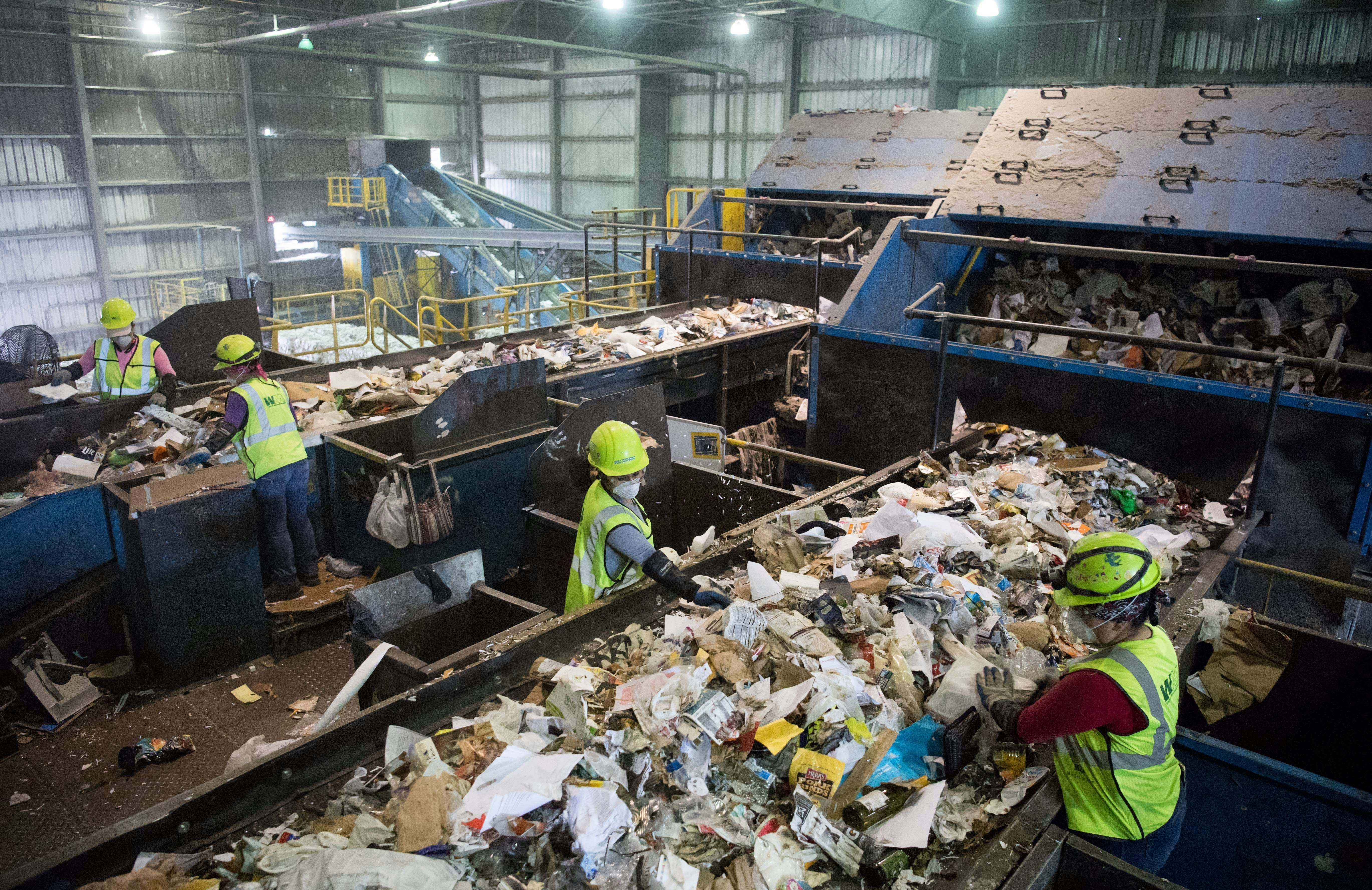 Workers sort recycling material at the Waste Management Material Recovery Facility in Elkridge, Maryland, June 28, 2018. - Some 900 tons of trash are dumped at all hours of the day and night, five days a week, on the conveyor belts at the plant. For months, this major recycling facility for the greater Baltimore-Washington area has been facing a big problem: it has to pay to get rid of huge amounts of paper and plastic it would normally sell to China. But Beijing is no longer buying, claiming the recycled materials are "contaminated."