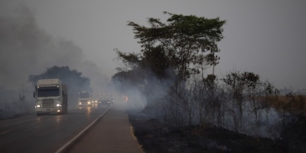 Trucks drive alongside scorched fields on the BR 163 highway in the Nova Santa Helena municipality, in the state of Mato Grosso, Brazil, Friday, Aug. 23, 2019. Under increasing international pressure to contain fires sweeping parts of the Amazon, Brazilian President Jair Bolsonaro on Friday authorized use of the military to battle the massive blazes. (AP Photo/Leo Correa)