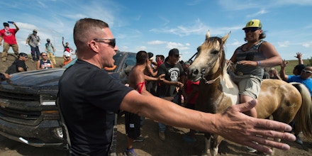 A Native American protestors holds up his arms as he and other protestors are threatened by private security guards and guard dogs, at a work site for the Dakota Access Pipeline (DAPL) oil pipeline, near Cannon Ball, North Dakota, September 3, 2016. Hundreds of Native American protestors and their supporters, who fear the Dakota Access Pipeline will polluted their water, forced construction workers and security forces to retreat and work to stop. / AFP / Robyn BECK (Photo credit should read ROBYN BECK/AFP/Getty Images)