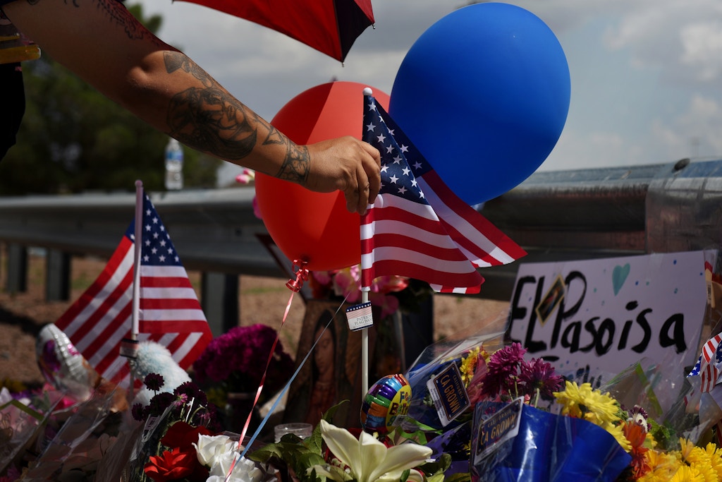 A man places an American flag in the pile of flowers that has gathered a day after a mass shooting at a Walmart store in El Paso, Texas, U.S. August 4, 2019.   