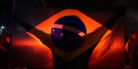 Um homem ostenta a bandeira nacional durante a comemoração da ida do então candidato a presidência Jair Bolsonaro ao segundo turno das eleições de 2018.