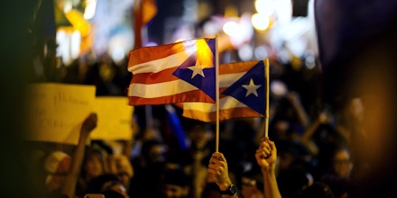 Demonstrators wave Puerto Rico flags as they gather during a protest demanding the resignation of Governor Ricardo Rossello in front of La Fortaleza in San Juan, Puerto Rico, on Wednesday, July 24, 2019. Rossello's looming resignation leaves Puerto Rico's government in shambles and may strengthen the hand of federal overseers tasked with imposing austerity on the bankrupt island to pull it from a years-long financial crisis. Photographer: Xavier Garcia/Bloomberg via Getty Images