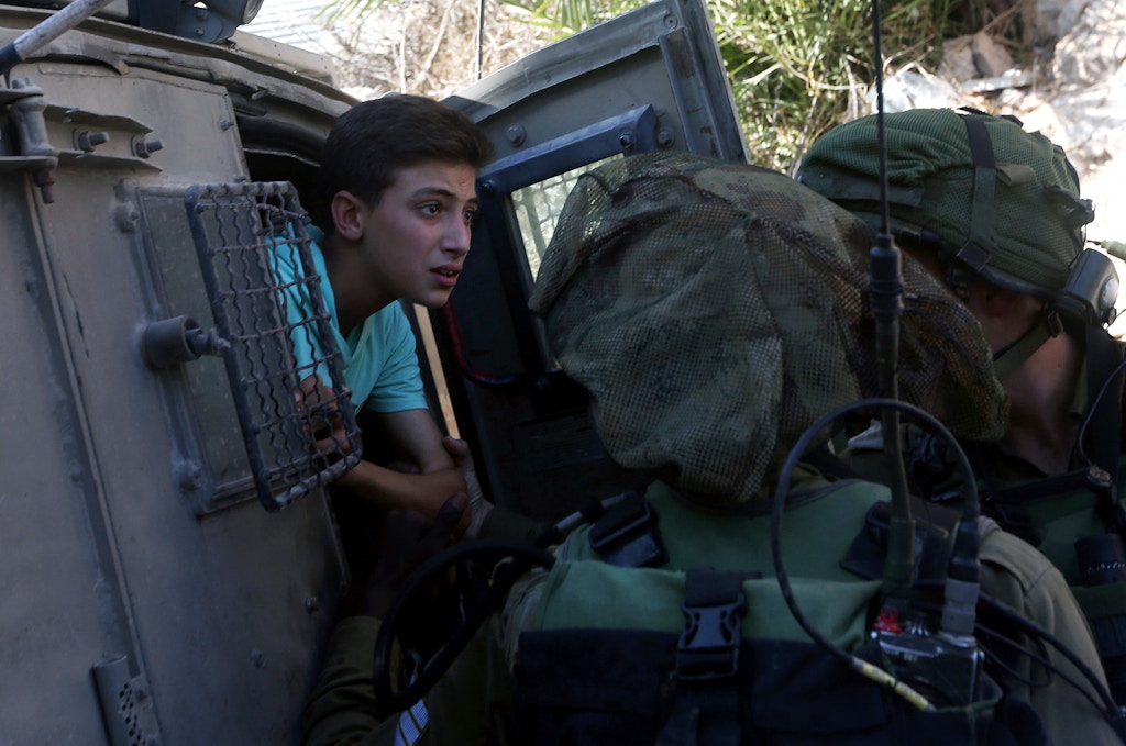 TOPSHOT - Israeli soldiers free a Palestinian youth, after temporarily detaining two youth, in the West Bank village of Burin on September 15, 2016, following scuffles with Israeli settlers. / AFP / JAAFAR ASHTIYEH