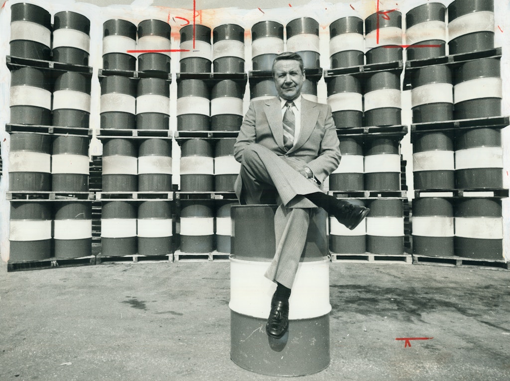CANADA - APRIL 20:  Every Canadian man, woman and child consumes on average each year the energy equivalent of these 49 barrels of crude oil. Affluent Canadians eat up more energy per capita than Americans. That much oil dwarfs John Armstrong (above), chairman of Imperial Oil, who perches on one barrel with 48 more arrayed behind him. Even at low Canadian prices, before refining, this quantity costs about $440.   (Photo by Harold Barkley/Toronto Star via Getty Images)