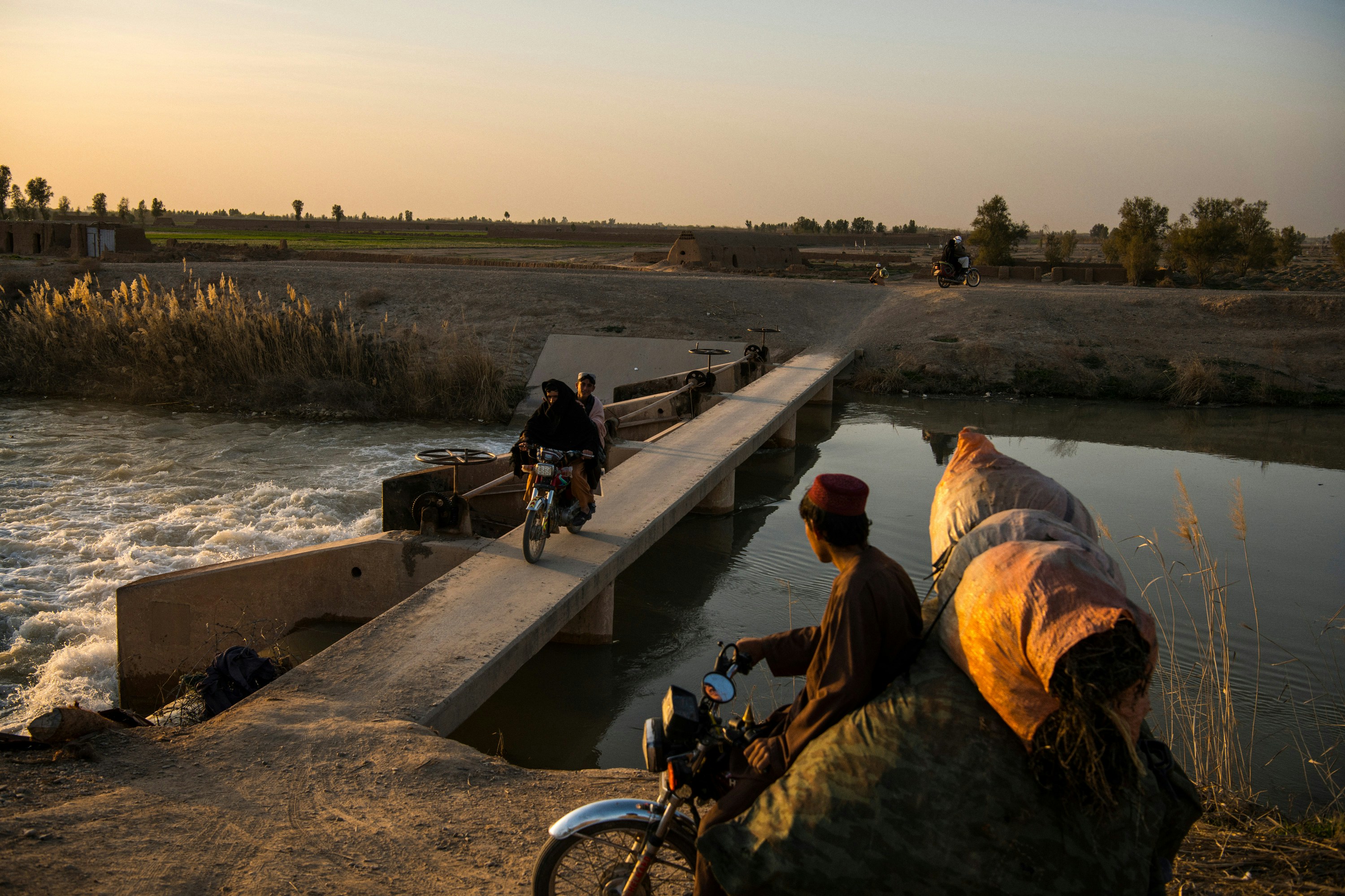 Local residents cross the Boghra Canal, in Loy Manda, an area on the outskirts of Helmand's capital Lashkar Gah. Under normal circumstances, the canal marks the frontline between government and Taliban forces. This week, however, during a week-long reduction in violence agreed to by the Taliban, the Afghan government and U.S. forces, local residents came and went on a strip of road beside it and back and forth across the canal itself. Residents were relaxed and enjoying the chance to move about without the fear of being caught in crossfire between the warring parties. The road is usually all but abandoned.
