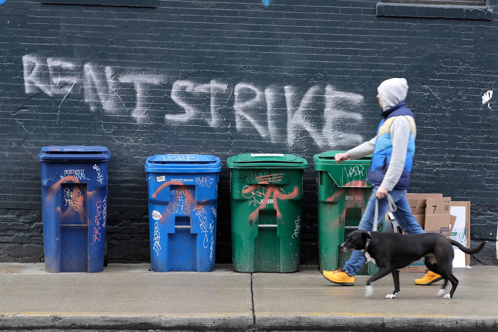 A pedestrian walks past graffiti that reads "Rent Strike" Wednesday, April 1, 2020, in Seattle's Capitol Hill neighborhood. With millions of people suddenly out of work and rent due at the first of the month, some tenants in the U.S. are vowing to go on a rent strike until the new coronavirus pandemic subsides. Some cities have temporarily banned evictions, but advocates for the strike are demanding that rent payments be waived, not delayed, for those in need during the crisis. (AP Photo/Ted S. Warren)