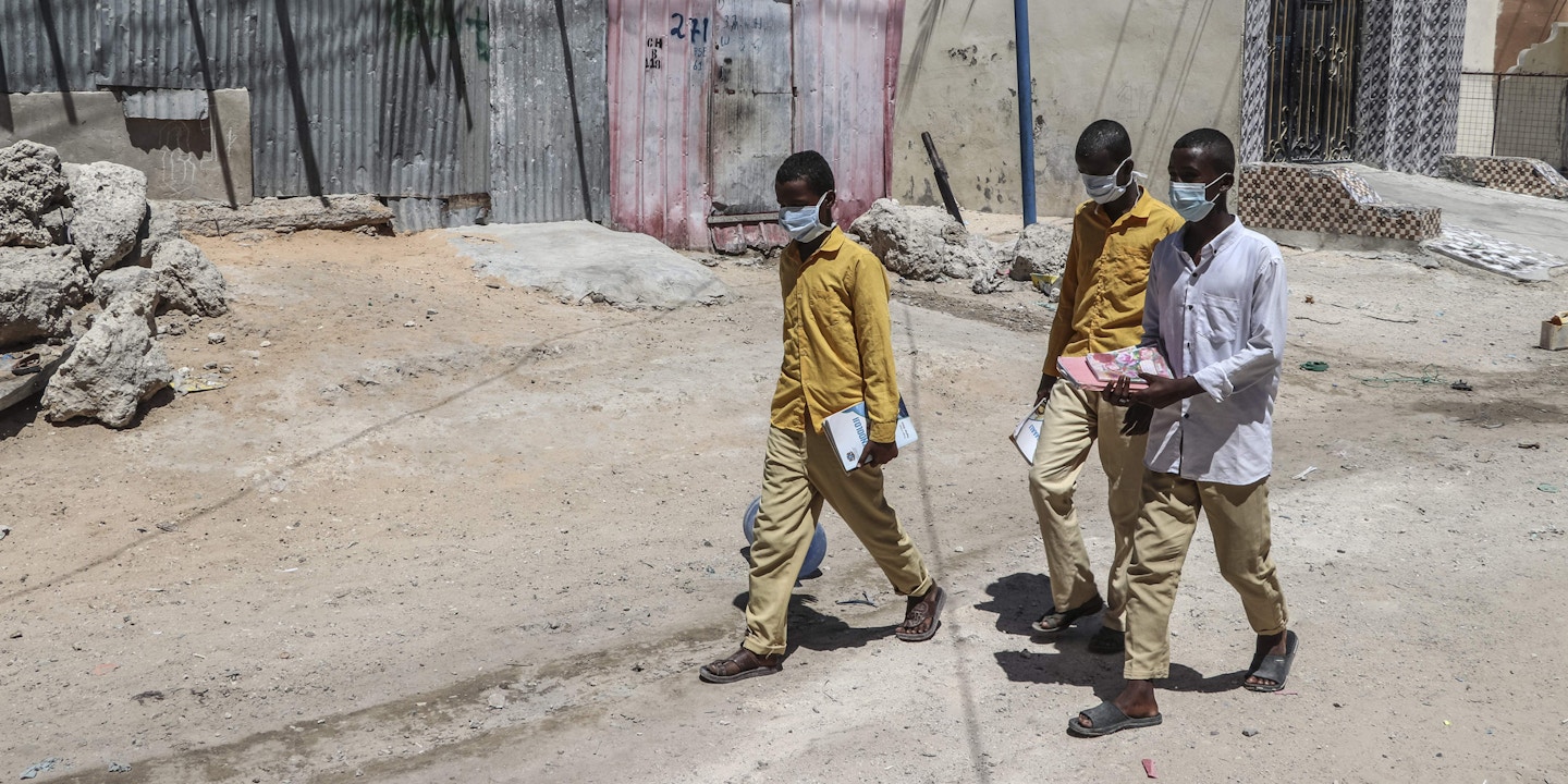 Students walk in a Mogadishu neighbourhood wearing face masks as protective measure against Coronavirus on Thursday March 19, 2020. - Somali prime minister on Wednesday announced closure of schools and universities as a protective measure against Convid-19. (Photo by Abdirazak Hussein FARAH / AFP) (Photo by ABDIRAZAK HUSSEIN FARAH/AFP via Getty Images)