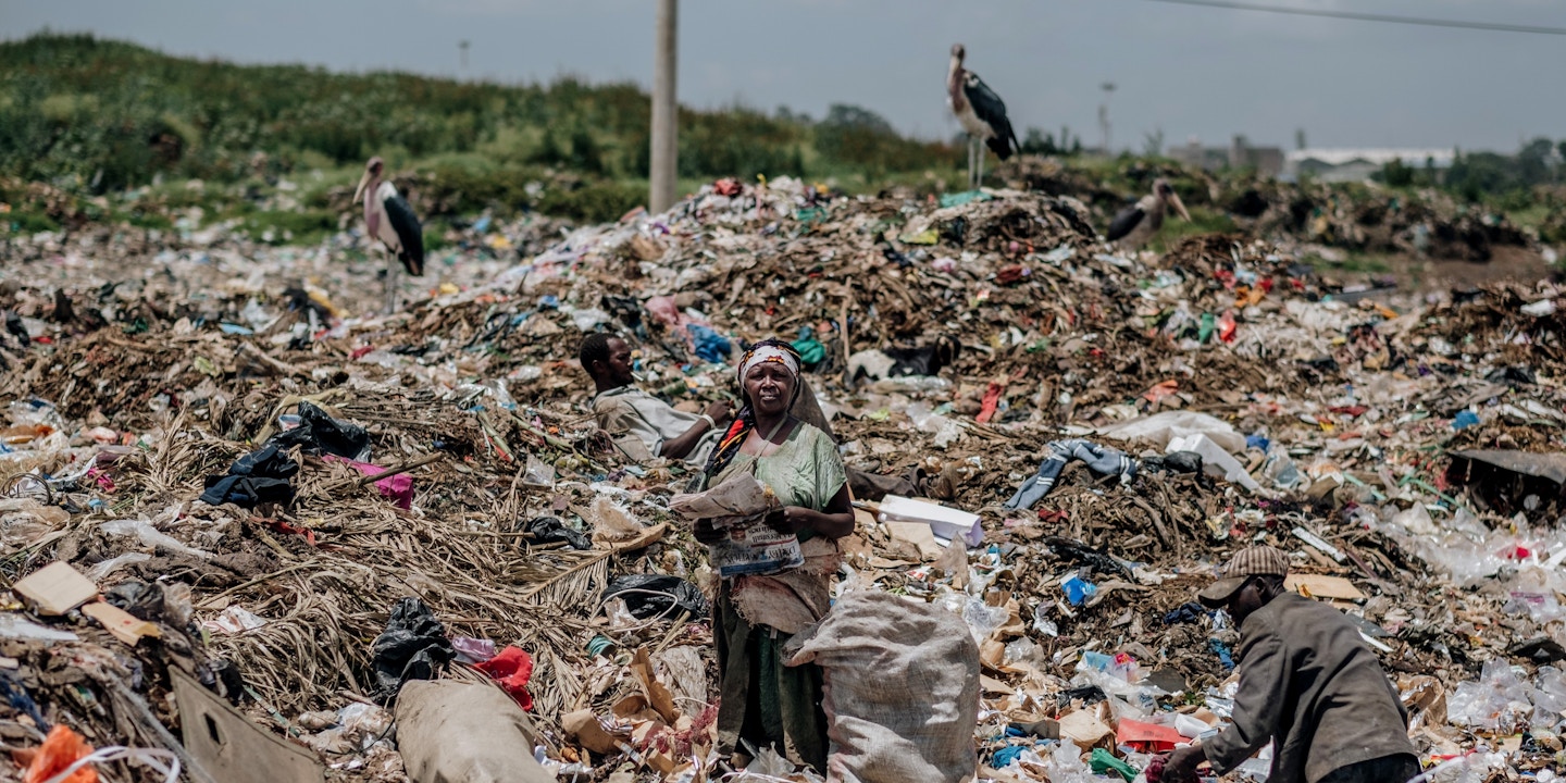 A woman takes a break from collecting waste to read the newspaper at the Dandora municipal dump site in Nairobi, Kenya, on Feb. 15, 2020.