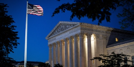 An American flag flies outside the U.S. Supreme Court as it stands illuminated at night in Washington, D.C., U.S., on Monday, May 4, 2020. Lawmakers are preparing for a debate on whether the U.S. economy will need a long-term effort to rebuild it, something that could cost trillions of dollars. Photographer: Al Drago/Bloomberg via Getty Images
