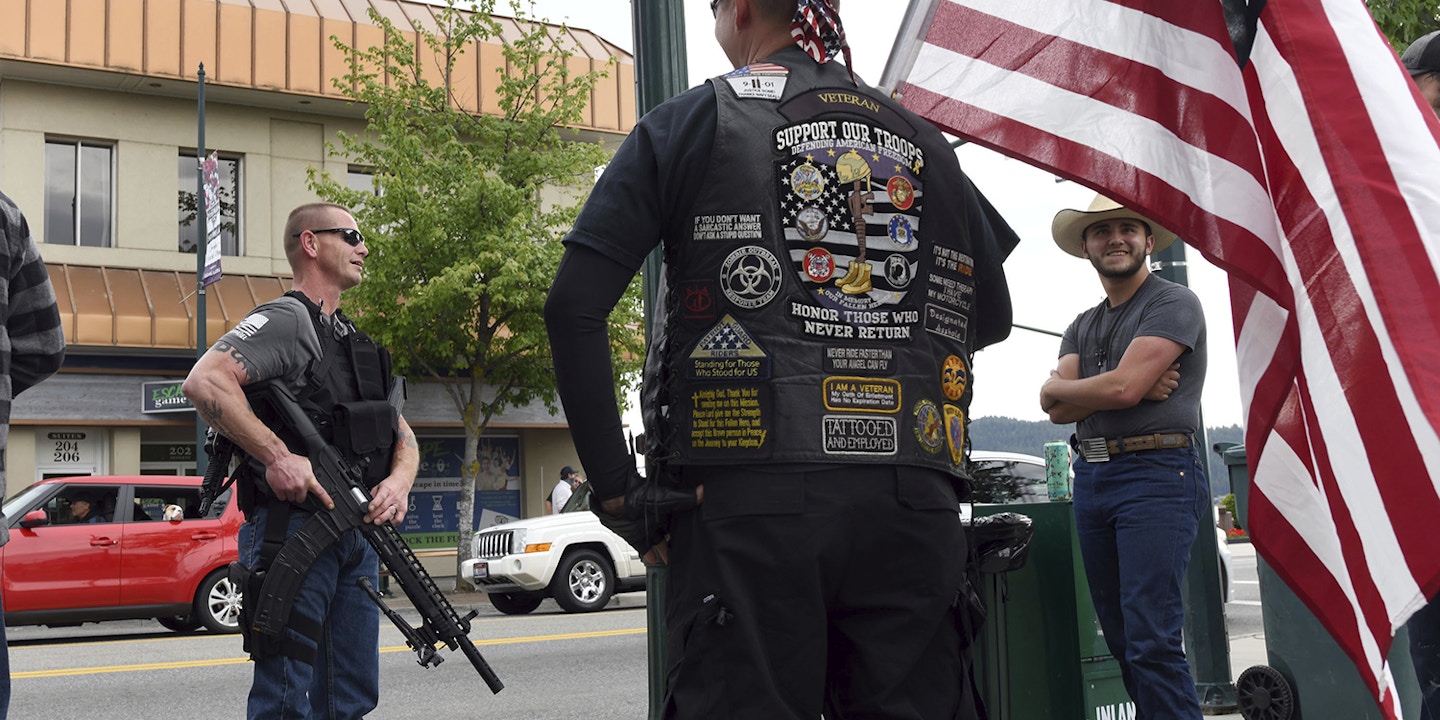 "We are not counter-protesters, we're just going to make sure Coeur d'Alene is safe" says Conrad Nelsen of Coeur d'Alene, Idaho, as he holds the flag while standing next to armed citizen Dan Carson, left, during a protest Tuesday, June 2, 2020, Coeur d'Alene, Idaho, about the killing of George Floyd. (Kathy Plonka/The Spokesman-Review via AP)